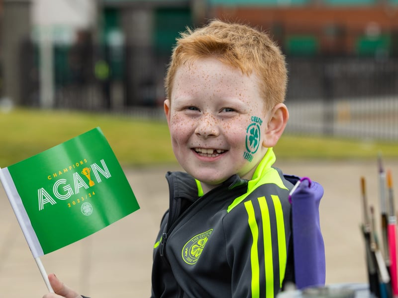 A young Celtic fan has the club emblem painted on his face as he welcomes the team to the stadium.