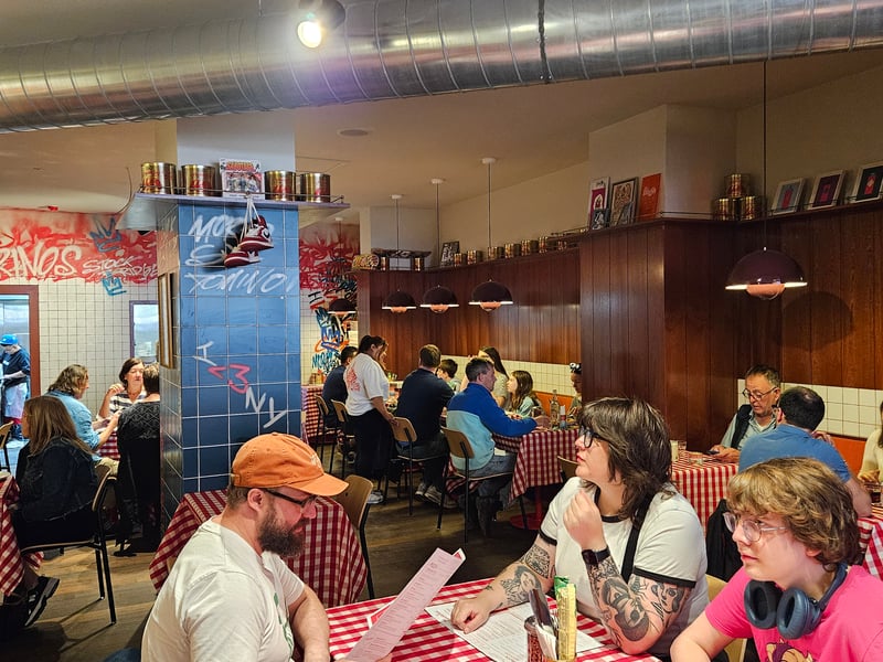 Set against both wooden panelling and sleek, white tiles, the tasteful decor extends to an outdoor seating area under a matching red and white awning.