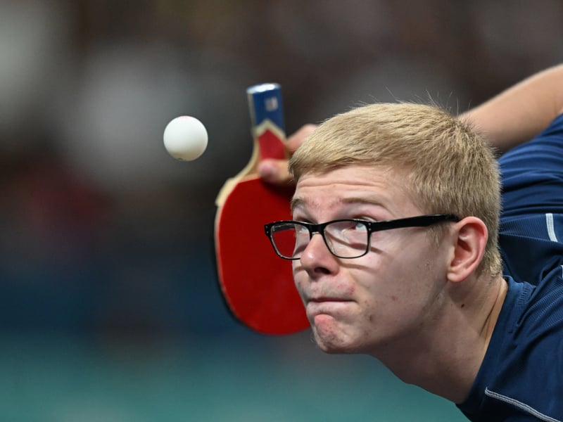 France's Felix Lebrun eyes the ball while serving during his men's table tennis singles match in the team semifinal between China and France
