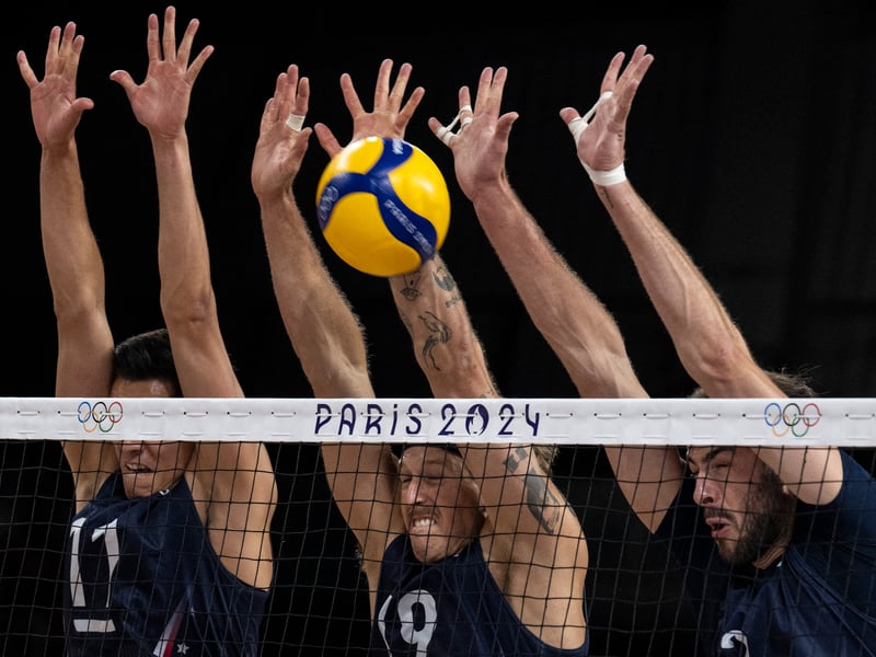 US #11 Micah Christenson (L), US #19 Taylor Averill (C) and US #2 Aaron Russell (R) block the ball during the men's volleyball semi-final match between Poland and USA