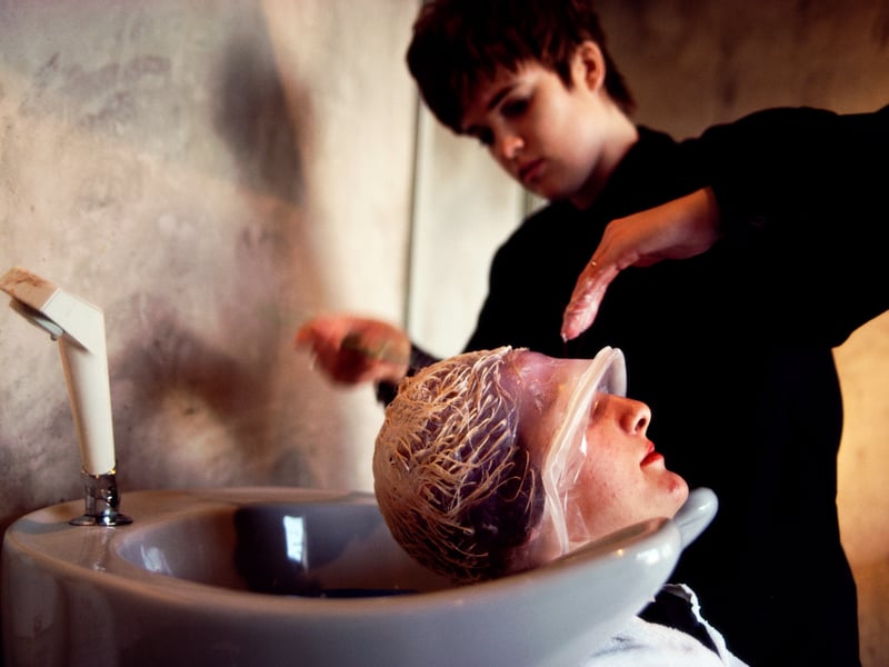 A woman's hair is given a perm and colour by a stylist in a Glasgow beauty salon in 1990. 