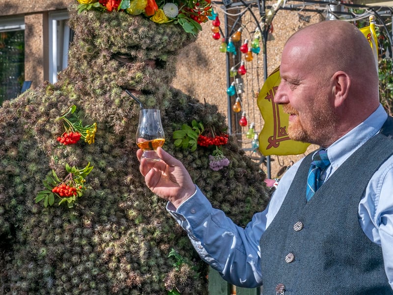 Burryman Andrew Taylor shares a whisky with Tony Hamlin as he parades through the town of South Queensferry, near Edinburgh, encased in burrs. Flowers and Lion Rampant flags were also used to decorate staffs to help him walk, and Mr Taylor was accompanied by two minders and a third person ringing a bell, shouting, “Hip hip hooray, it’s the Burryman’s Day”