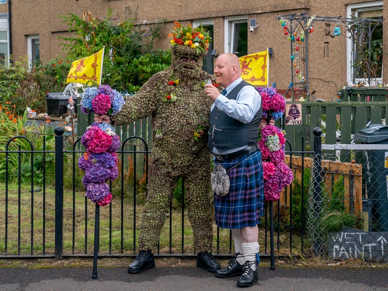Burryman Andrew Taylor shares a whisky with Tony Hamlin as he parades through the town of South Queensferry, near Edinburgh, encased in burrs