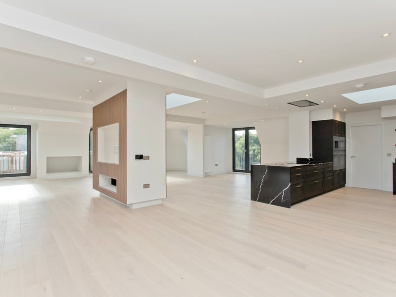 Natural light floods the penthouse's living space from all angles, with the feature fireplace highlighted. 
