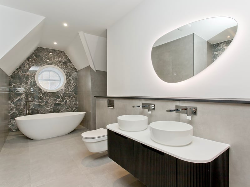 The modern free-standing bath sits below a feature period window. 