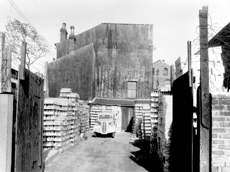 A yard adjacent to the Coca Cola (Northern Bottles) Depot on Sheepscar Avenue in September 1959. In this view crates of drinks and bottles are stacked in the yard including 'Quosh' which was a fruit squash drink to dilute with water.