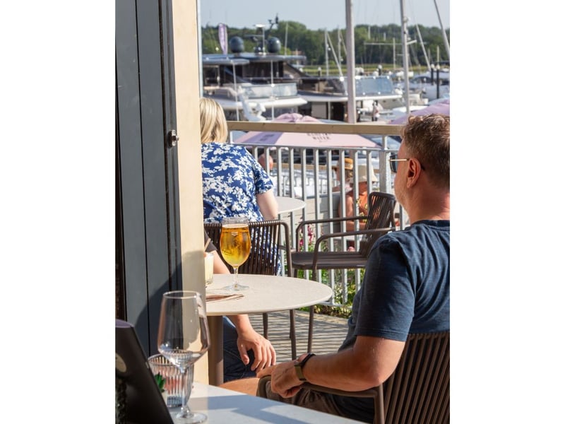 Locals enjoy a drink while sitting in the sun gazing at the boat in Swanwick Marina.