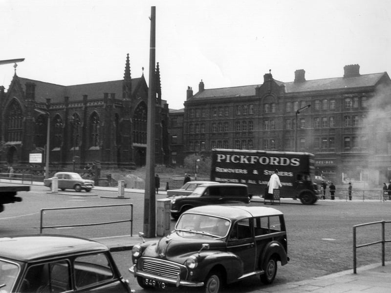 View from the Queen's Hotel to Park Row and Lower Basinghall Street. On the left is Mill Hill Chapel in Park Row. Next to it is the former site of the 1875 Royal Exchange buildings which have recently been demolished. Clouds of dust can be seen as work is carried out. With the absence of the Royal Exchange the shop and business properties in Lower Basinghall Street, from centre to right, are now visible. These include the Del Rio Coffee Bar at number 12 Lower Basinghall Street. A Pickfords removal van is seen at the junction with Park Row and Boar Lane. Pickfords had a removal and storage service at number 24 Lower Basinghall Street at this time.