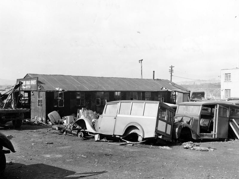 The east side of Low Fields Road Spares on Low Fields Road. Shows scrapyard full of cars and tow truck on left. "Low Fields Road Spares" sign visible on building. Pictured in October 1942.