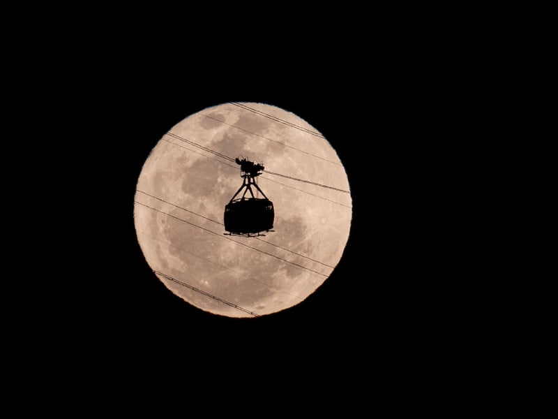 A cable car heads toward Sugarloaf Mountain as the supermoon rises into the night sky in Rio de Janeiro, Monday, Aug 19, 2024