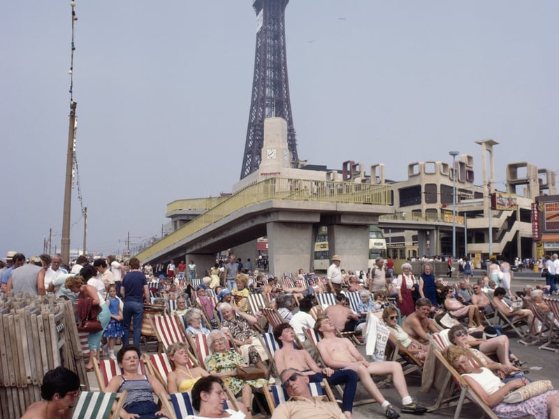 Holidaymakers relaxing in deckchairs in view of the tower in the seaside resort of Blackpool, Lancashire, August 1983. 