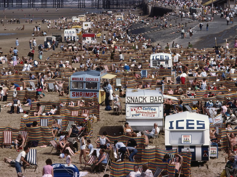 Crowds of holidaymakers and kiosks offering tea, coffee, ices, whelks and cockles and shrimps as snacks on the beach in the seaside resort of Blackpool, Lancashire, August 1983