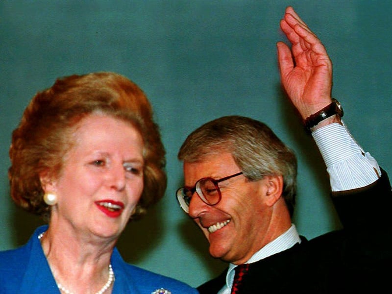 British Prime Minister John Major (R) waves as he walks onto the platform at the Conservative Party conference 07 October 1993. Major's predecessor Margaret Thatcher (L) stands for his arrival