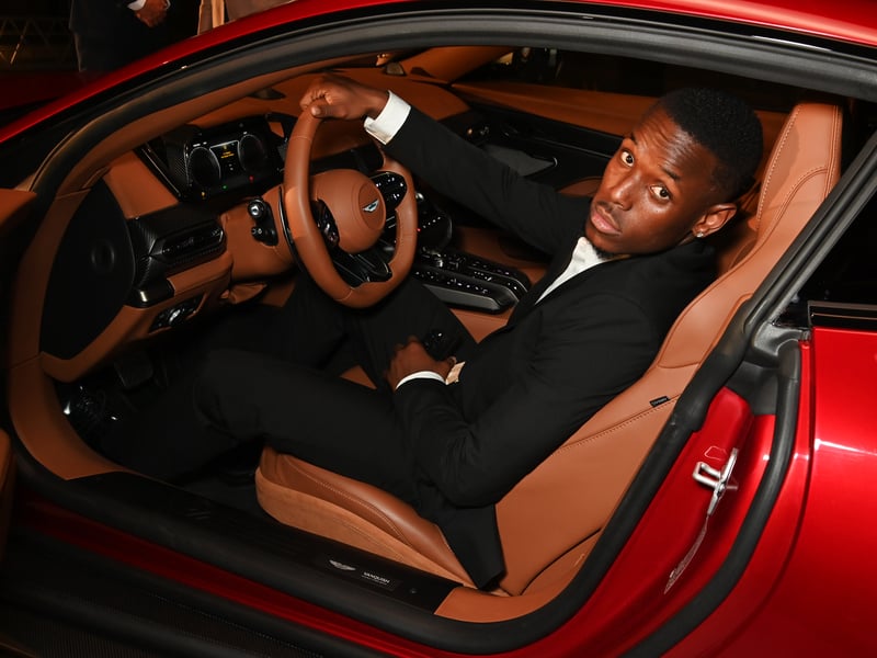 Empire of Light star Michael Ward looking sharp in the interior of a left-hand drive Aston Martin V12 Vanquish at the Venice reveal.