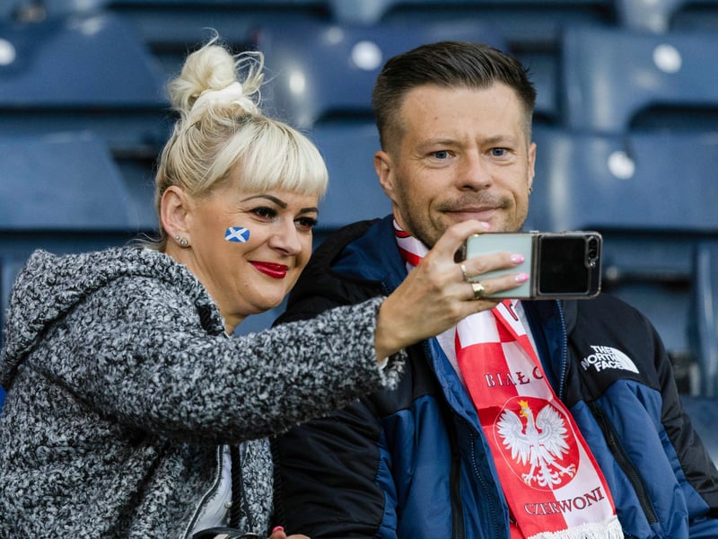 A Scotland fan and a Poland fan share a photo ahead of the game.