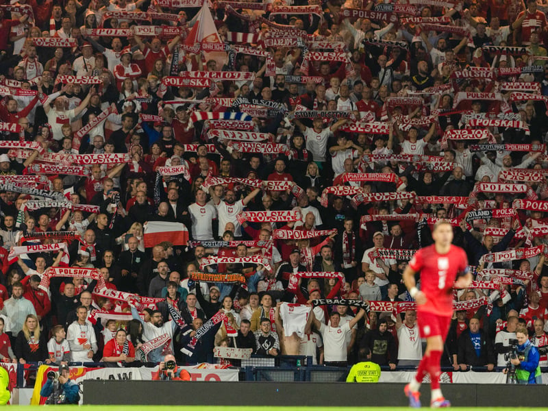 Poland fans raise their scarves above their head in celebration of the late win.