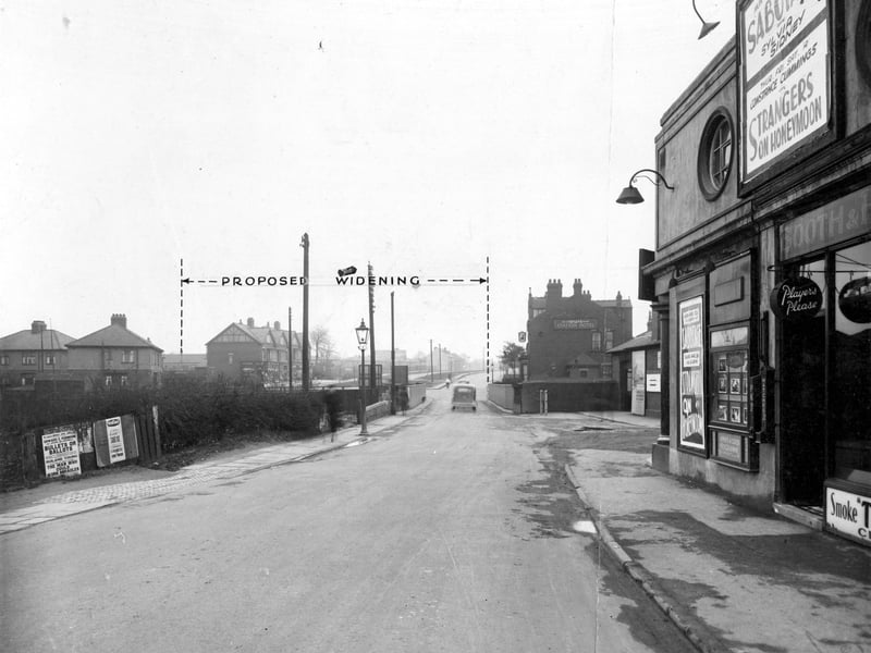 Station Road, across the railway bridge. Measurement on photograph shows extent of size the bridge would be after widening. Houses to the left are on Coldwell Road. To the right is the Station Hotel, a Tetley Public House. Next is the entrance to Cross Gates Station for trains on the North Eastern Railway Line for Leeds and York. The side of the Ritz Cinema can be seen with posters for films 'Sabotage' starring Sylvia Sidney and 'Strangers On Honeymoon' with Constance Cummings.