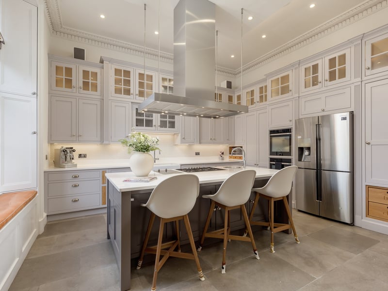 The kitchen includes custom made cabinetry by Studio Carpentry, high specification integrated Samsung/Smeg appliances, a double Belfast sink, and a large Silestone breakfasting island.