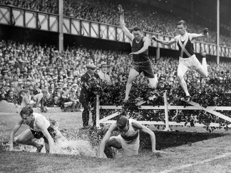 Competitors leaping over the water jump in an eight lap steeplechase event during the 49th annual sports day of the held at Ibrox.