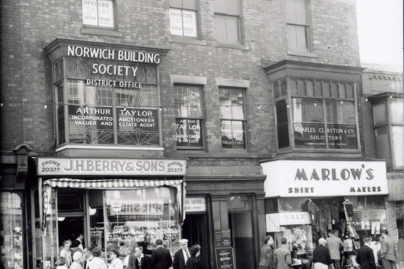 Talbot Road, Blackpool - south side between Abingdon Street and Topping Street. J.H. Berry & Son pork butcher and pie shop. Marlow's outfitters, Norwich Building Society, Charles Clayton and Co solicitors