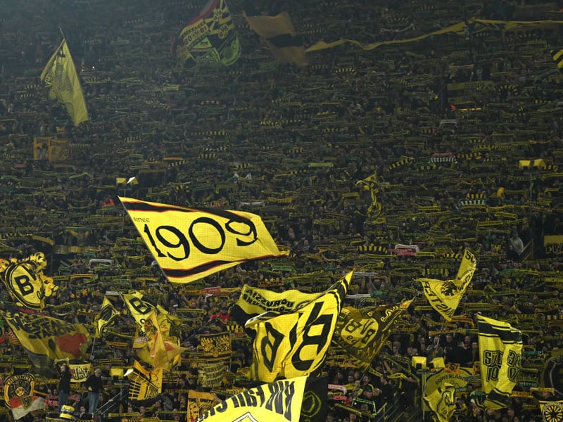 Dortmund's supporters in the famous 'yellow wall' wave flags to welcome the players to the pitch.