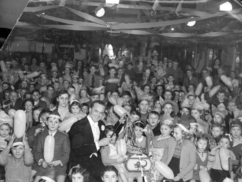 Children being entertained by the magician Hamilton Kaye, also known asWizard Kaye, Ron Dalmo and briefly as Milton Kaye. He was a popular conjuror and children's entertainer, who also ran a magic business supplying tricks and his speciality flash paper and string.