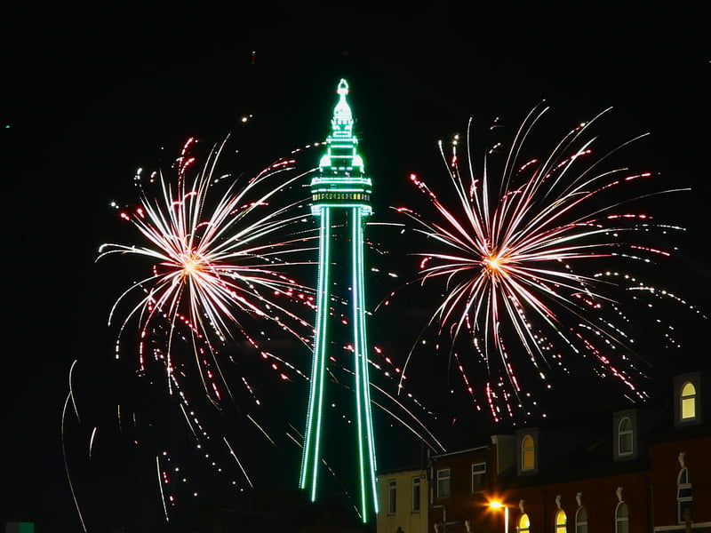 A green tower surrounded by fireworks
