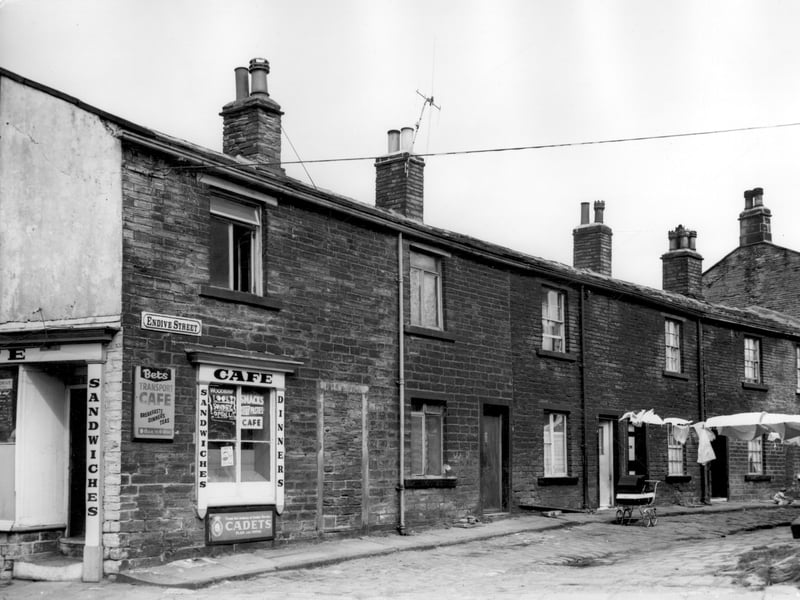Number 178 Stanningley Road is on the left. This is Bets Transport Cafe. Moving right onto Endive Street, the first house is number 3, numbers follow in sequence to 11 on the right edge. The surface of the Endive Street is constructed of cobbles, with a central drain channel, it is uneven. Pictured in April 1964