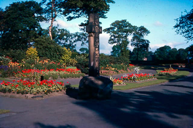 The entrance to Bramley Park showing the cross monument and flower beds with trees in the background. Pictured in July 1964.