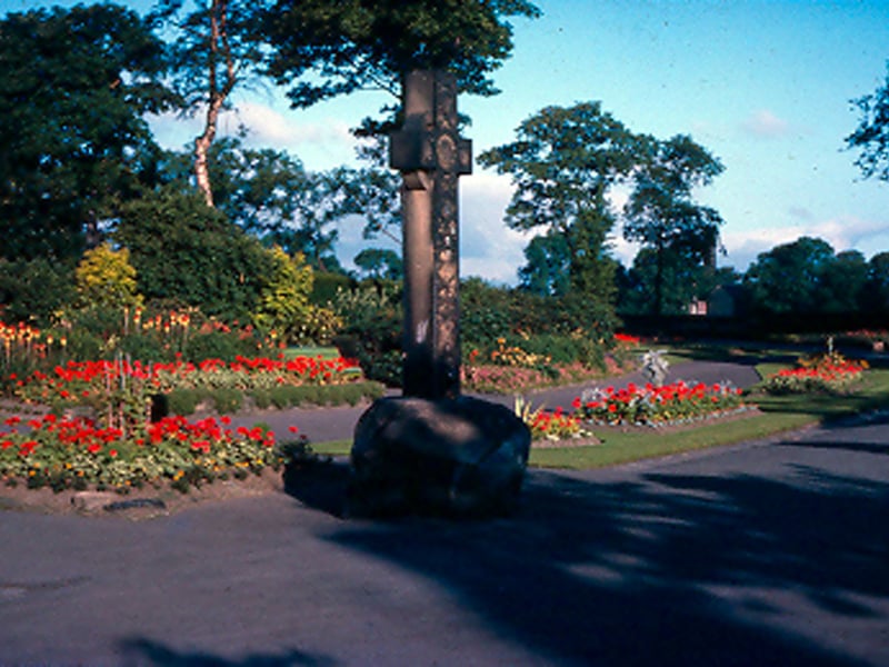 The entrance to Bramley Park showing the cross monument and flower beds with trees in the background. Pictured in July 1964.