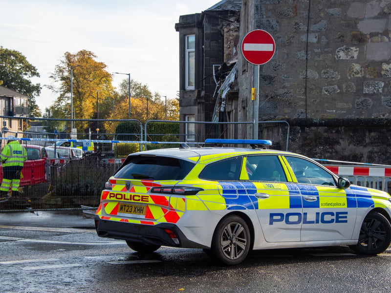 One of several police vehicles parked at the entrance to Kellie Place, which remains cordoned off to public access
