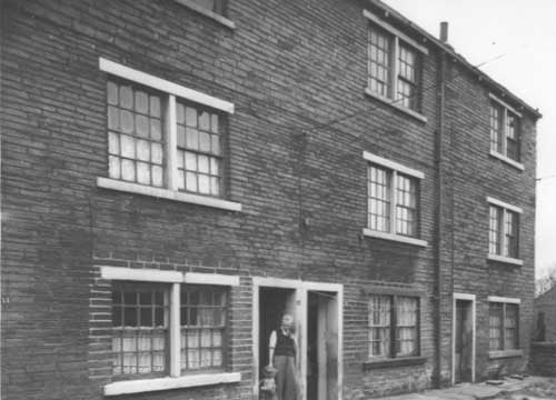 Three storey houses at the end of Endive Street. Number 13 is on the left, a man and a child are in the doorway. Next 15 then 17 on the right.