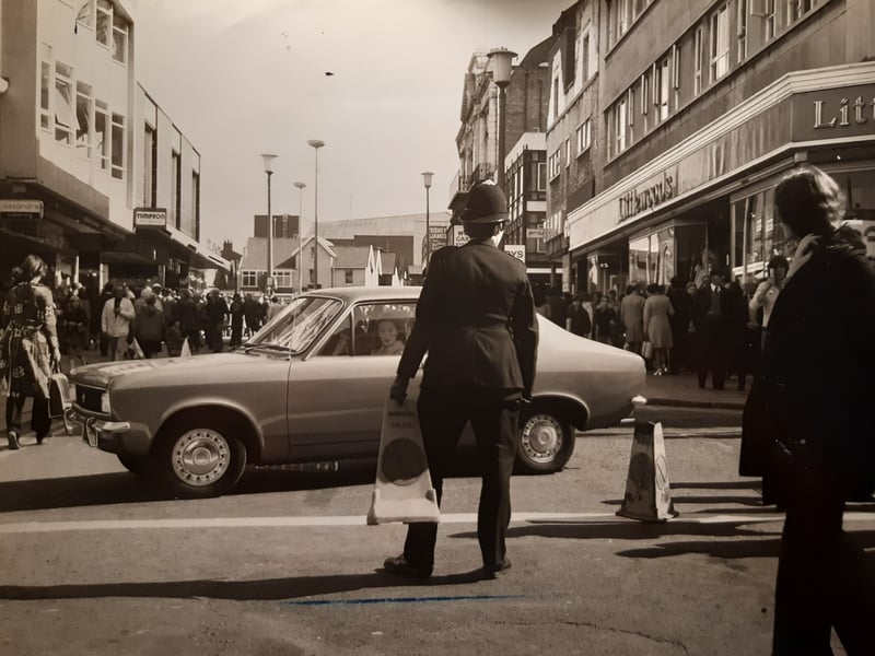 Littlewoods, Timpsons and a sign for Alexandra Clothing are pictured in this photo. The police officer looks like he was moving traffic cones. At the time road works were going on in Church Street
