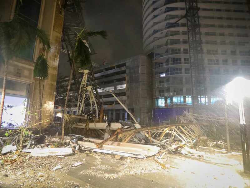 Debris covers the ground near a crane that fell onto a building along 1st Avenue South in St. Petersburg, Florida.
