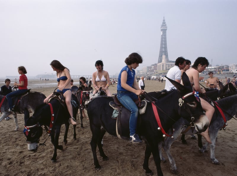 A group of holidaymakers enjoy donkey rides on the beach, 1983