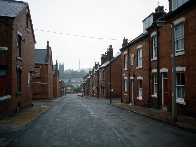 Looking south along Christopher Road towards Woodhouse Street in an area of red brick terraced housing. Streets leading off include Back Glossop Street, Glossop Street and Beulah View on the left and Cross Quarry Street on the right. Houses numbered 27 and 25 Christopher Road are seen on the right, with numbers continuing down to 1 after the junction. St. Mark's Church is visible in the distance. Pictured in August 1985.