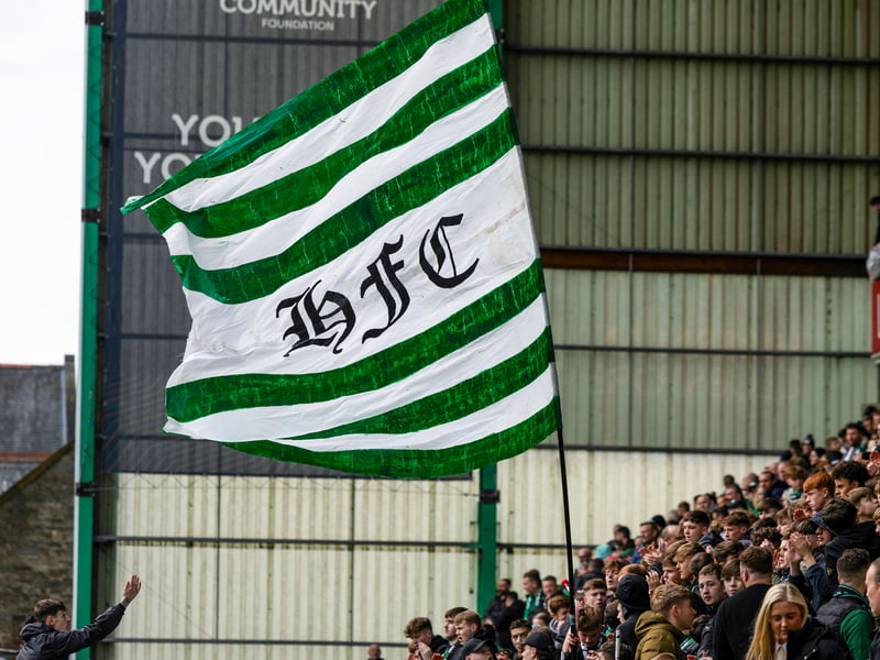The home fans wave a green and white flag baring the club initials ahead of kick-off.