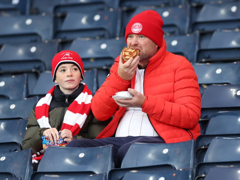 An Aberdeen fan tucks into a Hampden pie.