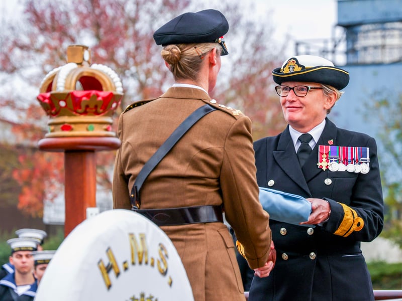 Rear Admiral Jude Terry OBE hands the tri-Service flag back to Brigadier Caroline Woodbridge-Lewin MBE.