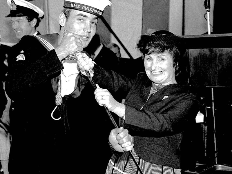 A picture of two people cutting a cake. A time capsule containing various items and keepsakes was discovered aboard the Royal Navy minehunter HMS Chiddingfold.