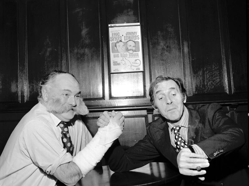 Actors and comedians Jimmy Edwards and Eric Sykes demonstrate arm-wrestling - despite Edwards' arm being in plaster - at the King's theatre Edinburgh for 'Big Bad Mouse' in February 1973.