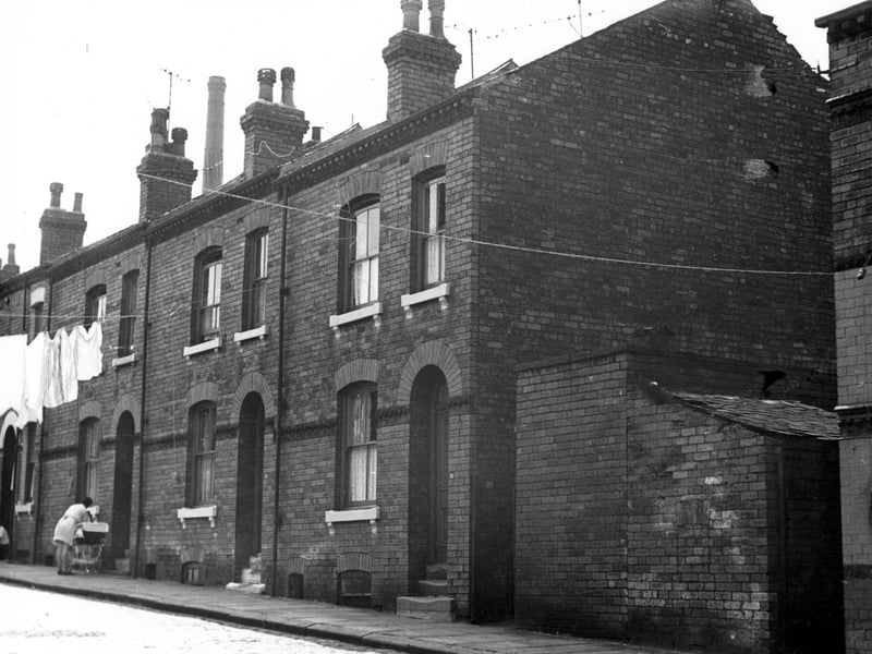  A lady with a pram is outside number 14 Claro Place, to the right is 12 with 10 next to the block of outside toilets.