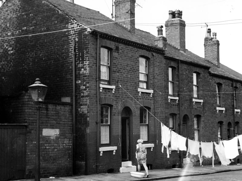 On the left is number 8 Servia Place, then to the right 6, with 4 on the right. The woman is in the process of hanging out her washing.