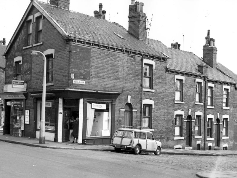 To the left is the junction with Wolseley Place and 23a Servia Road. The shop is a newsagents, business of M. Kershaw. Next at 25a Servia Road is S. Harrison, butchers shop. Servia Street can be seen, number 32 has a Mini traveller parked outside to the right are numbers 30, 28.