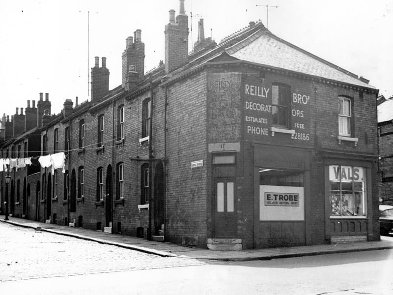 On the left is Servia Avenue number 17 Cambridge Road is E. Trobe, bookmakers office, with Reilly Brothers decorators on the first floor. To the right, number 19 is a shop selling ladies-wear, 'Vals'. This is at the junction with Claro Avenue.