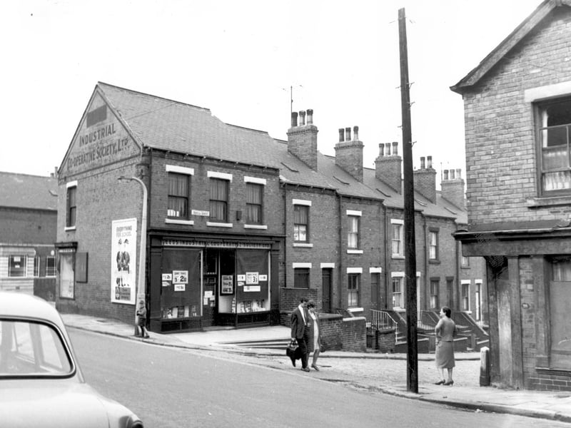 This view is looking from Servia Road as it becomes Oatland Lane. To the left the Yorkshire Bank can be seen at the corner with Servia Terrace. This was 25 Servia Road. On Servia Grove is a branch of the Leeds Industrial Co-operative Society. To the right a former shop, the doorway was concreted over and the window boarded up, this was 29 Servia Road, after this Oatland Lane began.