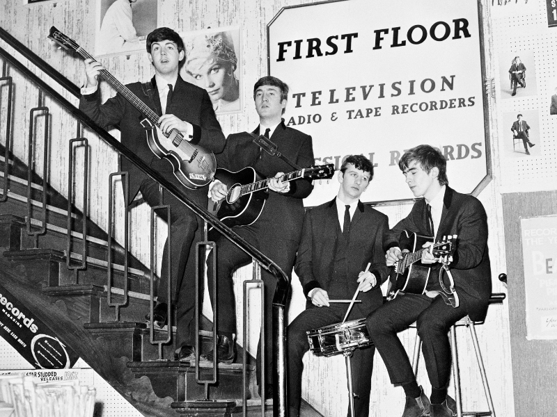 The Beatles pose on the stairs of NEMS (North End Music Stores), Brian Epstein's Liverpool record shop, having just signed a management deal with Brian, 1964.