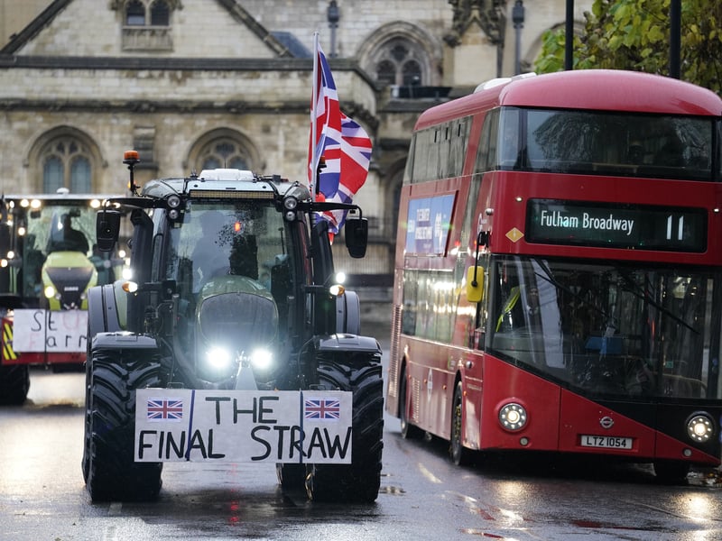A tractor bearing a placard reading 'The Final Straw' competes for road space in London with a double decker bus. Picture: PA