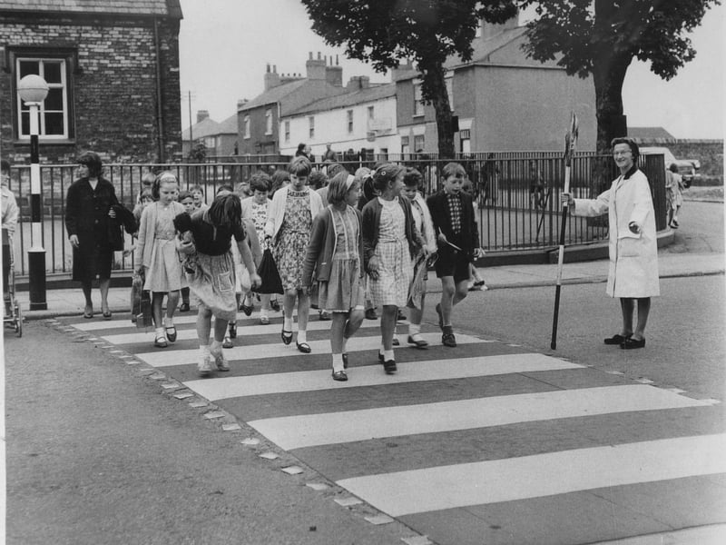 Lollipop lady Tilly Bullough helps children cross the road at the junction of Main Street and Church Lane in July 1965.