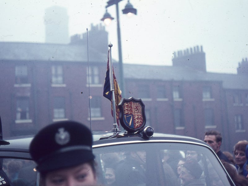 the Royal Standard on the Royal Car. Houses on Portland Crescent can be seen in the background. Police are visible in the foreground and crowds are people are gathered round the car. Queen Elizabeth II and the Duke of Edinburgh were visiting Leeds to open the new Seacroft Civic Centre.